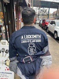 a man in a blue jacket sitting on a sidewalk